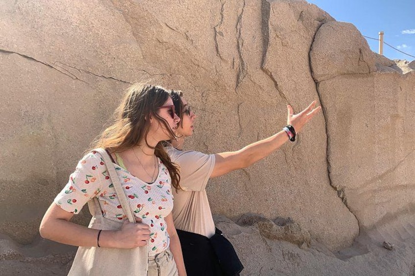 Two people standing in front of a large rock formation. 2