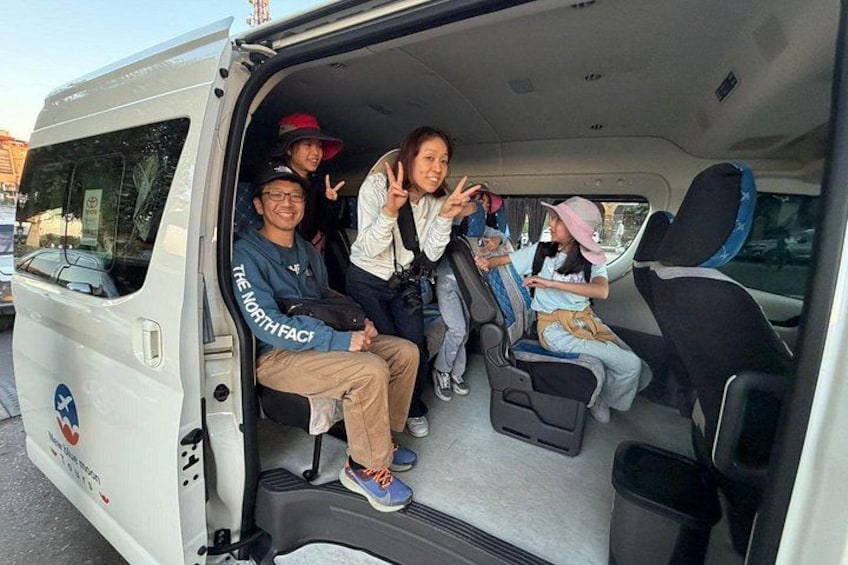 A white van with people sitting inside, one person making a peace sign. 1