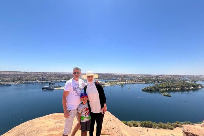 A family standing on a hill overlooking a body of water with boats and distant land. 4