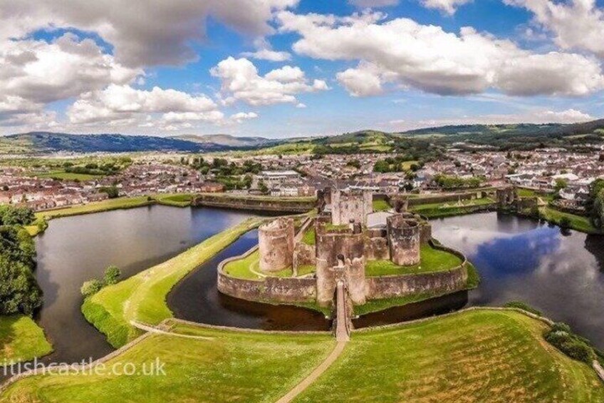 A historic castle surrounded by a moat, with a town in the background. 1