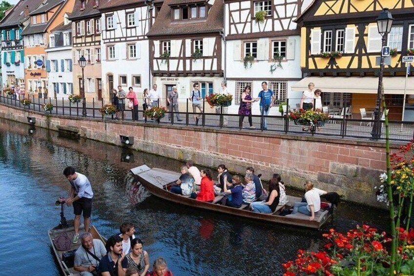 A narrow canal with a boat carrying passengers, surrounded by traditional half-timbered houses. 1