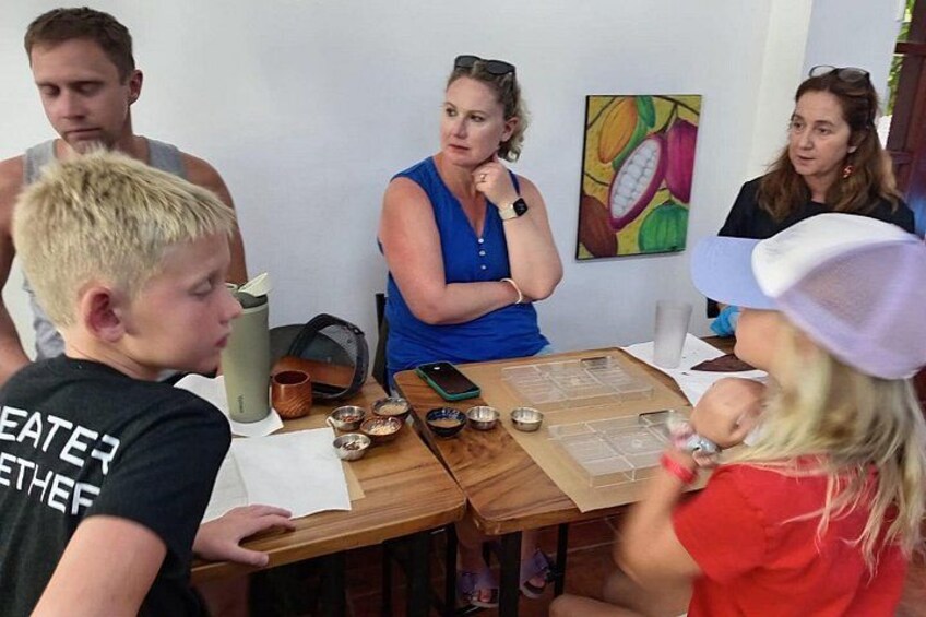 Un groupe de personnes est assis autour d’une table en bois, sur laquelle se trouvent divers objets. 4