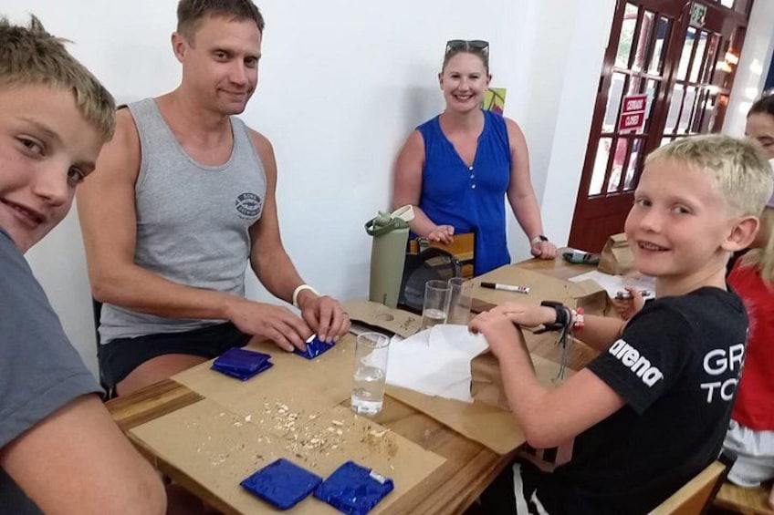 Un groupe de personnes était rassemblé autour d’une table, où elles réalisaient une activité manuelle à l’aide de divers matériaux et outils. 2