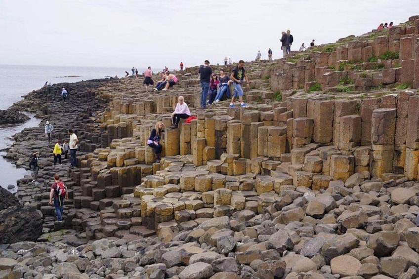 A rocky coastal area with people walking and sitting on stone structures. 2
