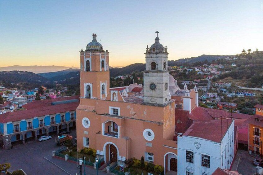 A historic church with two bell towers, surrounded by colorful buildings and a hilly landscape. 5