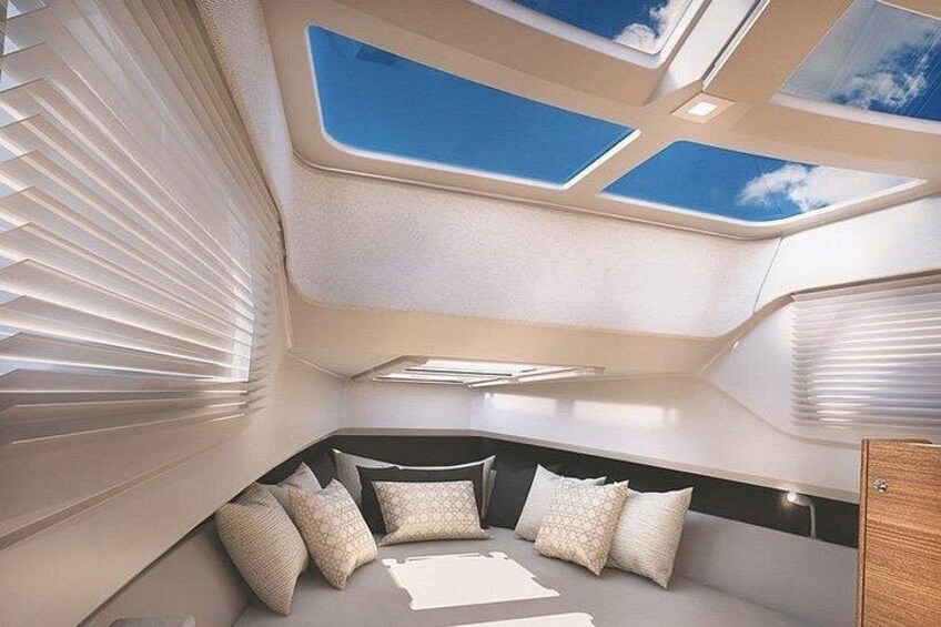 A boat interior with a skylight, cushioned seating, and a wooden cabinet. 2