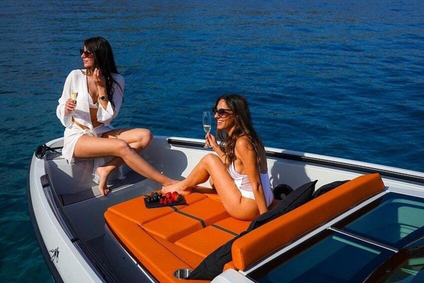 Two people on a boat with an orange cushion, a bottle, and a glass. 5