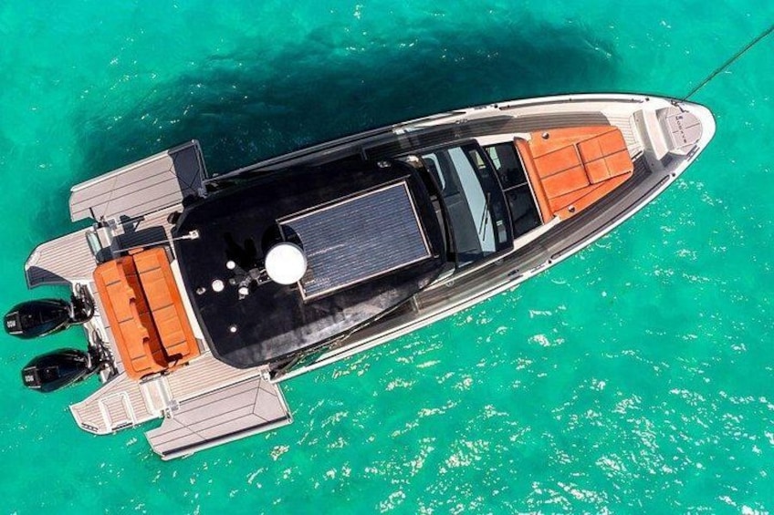 A boat with a black hull and orange deck, floating on turquoise water. 3