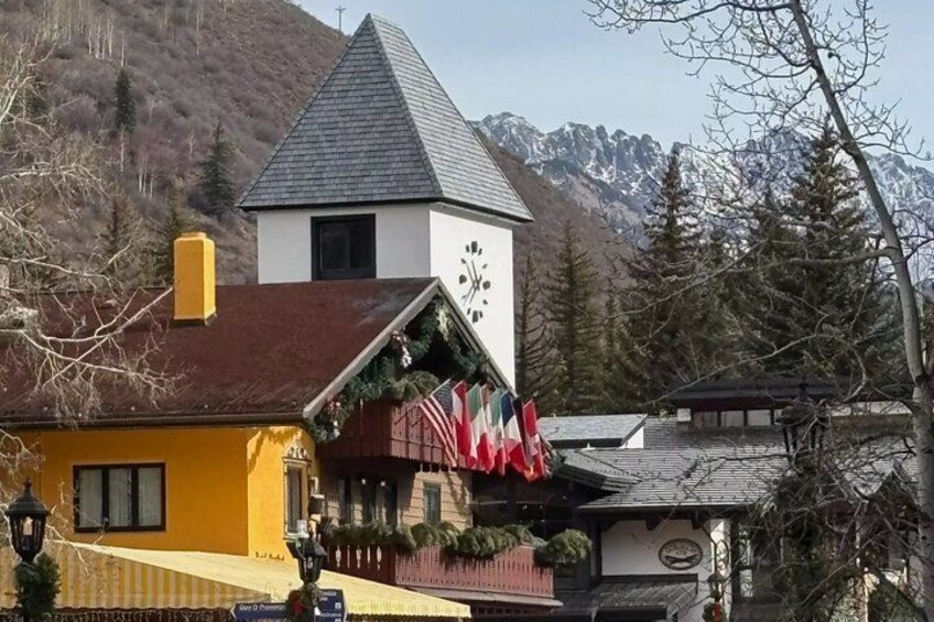 A building with a clock tower, a yellow facade, and flags. 2