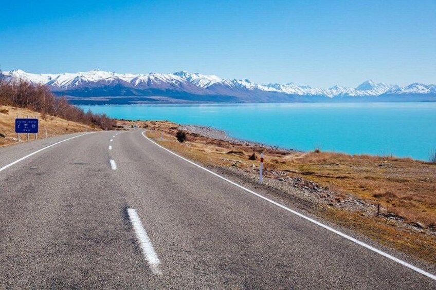 Una carretera que lleva a un lago con montañas al fondo. 5