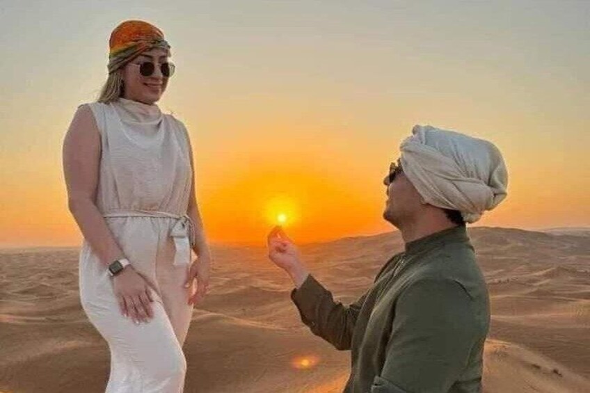 Two people standing on a desert with a sunset in the background. 2