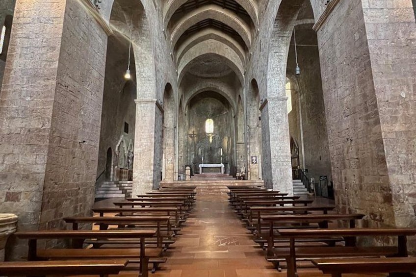 A church interior with rows of pews, stone columns, and a wooden floor. 5