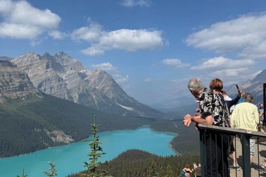 Un grupo de personas contemplando un lago turquesa con montañas al fondo. 1