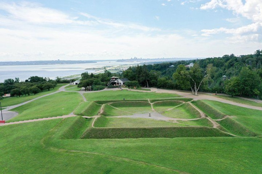 A golf course with a clubhouse, surrounded by trees and a body of water in the background. 2