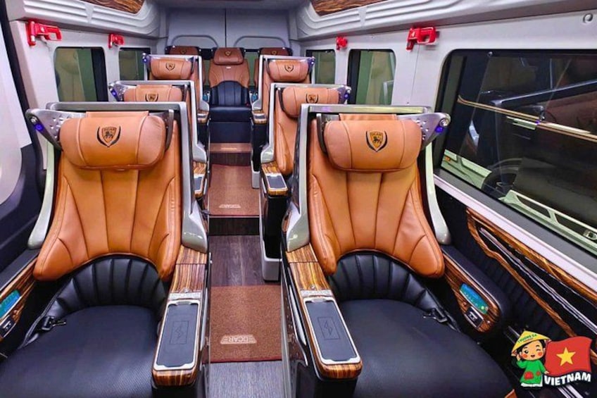 A train interior with leather seats, wooden panels, and a logo on the backrests. 5