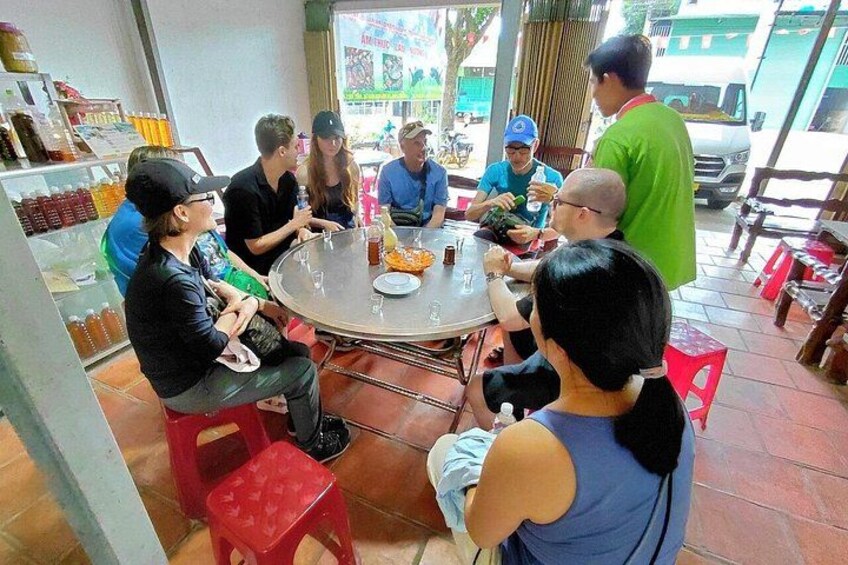 A group of people sitting around a round table in a restaurant with a menu board and bottles in the background. 5