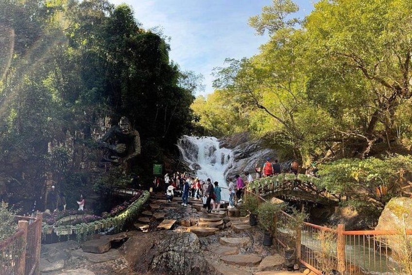 A waterfall, a rocky path, and a forested area with visitors. 3