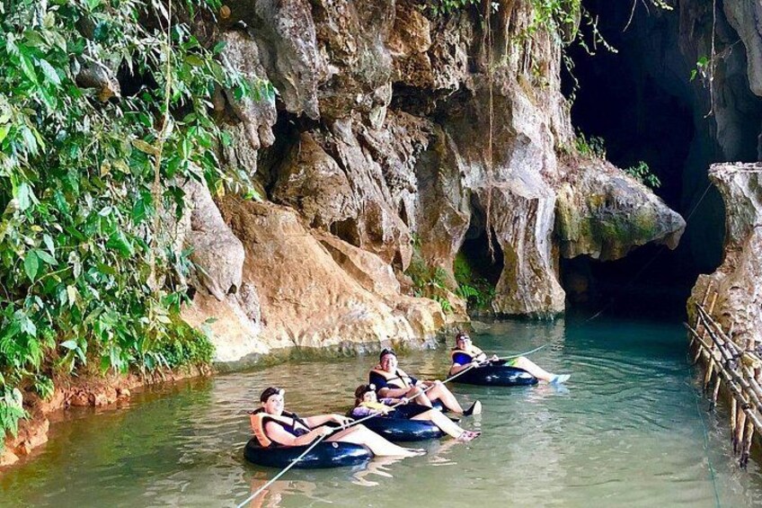 People in tubes floating down a river surrounded by rocky cliffs and greenery. 4