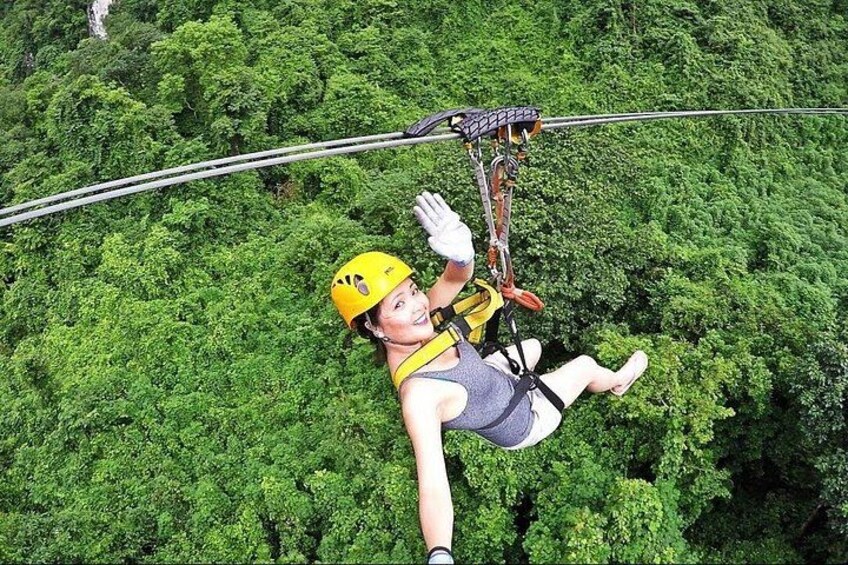 A person bungee jumping with a harness and helmet, surrounded by dense green foliage. 1