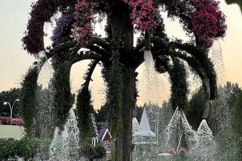 A tree with pink flowers, a fountain, and a white gazebo. 5