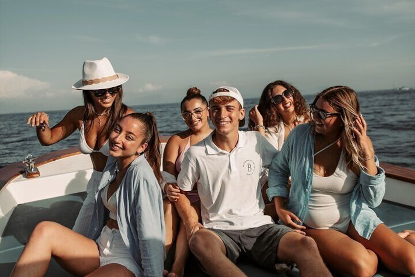 Een groep mensen op een boot, met water en een verre kustlijn op de achtergrond. 2
