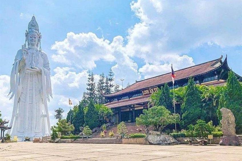 A large white statue, a traditional building, and a clear sky. 3