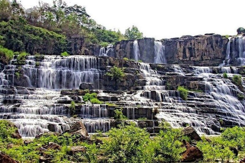 A multi-tiered waterfall cascading over rocky terrain with lush greenery at the base. 5