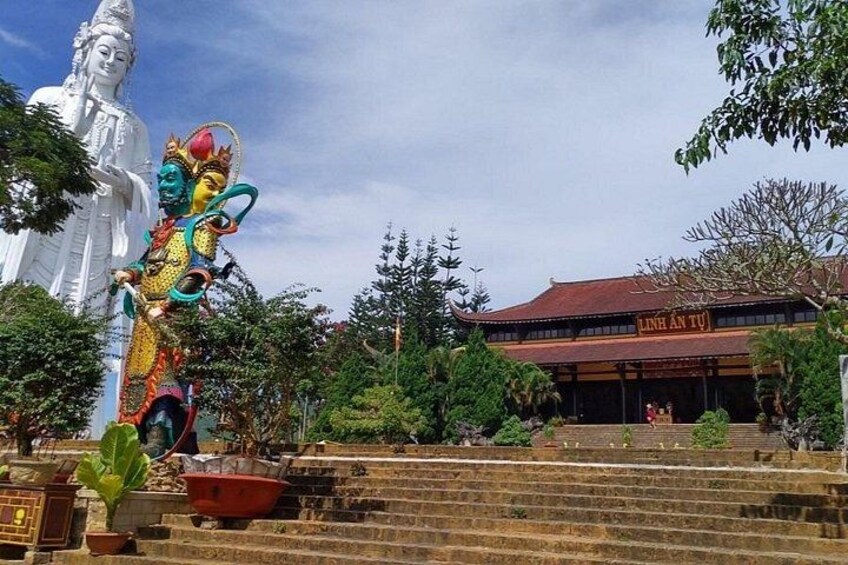 A large white statue, a colorful statue, and a building with a sign that reads 'Linh An Tu'. 2