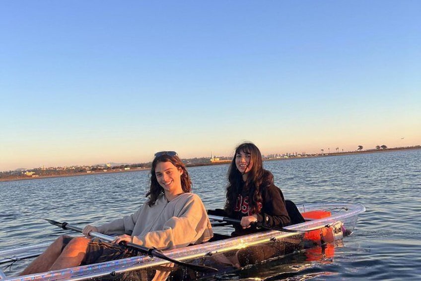 Two people in a small boat on a body of water with a distant shoreline. 2