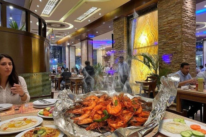 Un restaurante con una amplia exhibición de mariscos, mesas y comensales. 2