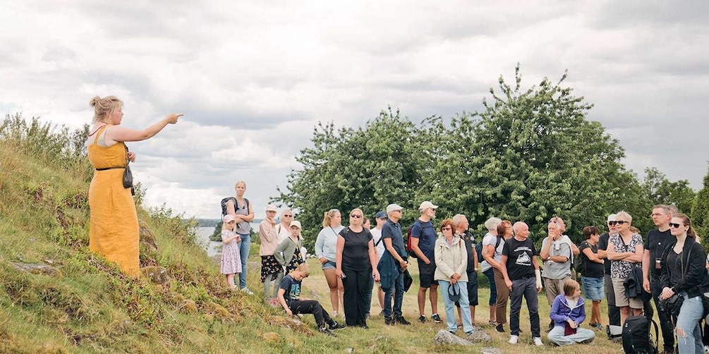 A group of people gathered outdoors, listening to a speaker. 5