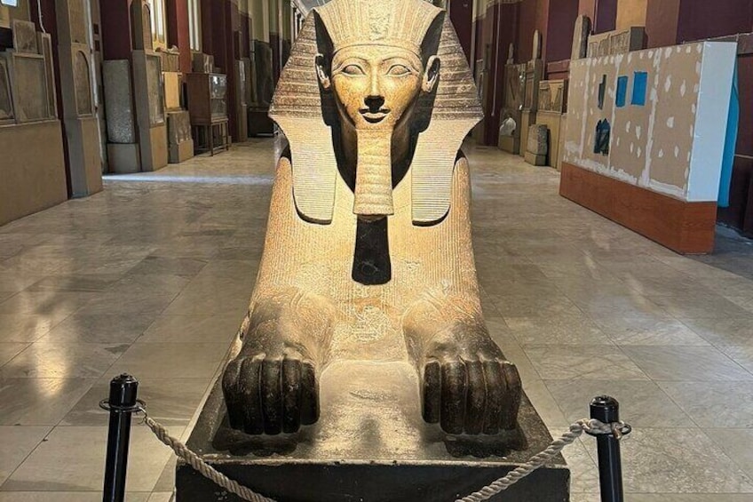 Un sarcófago egipcio grande y antiguo, con jeroglíficos, exhibido en un pasillo de museo con columnas de piedra y exhibiciones. 3