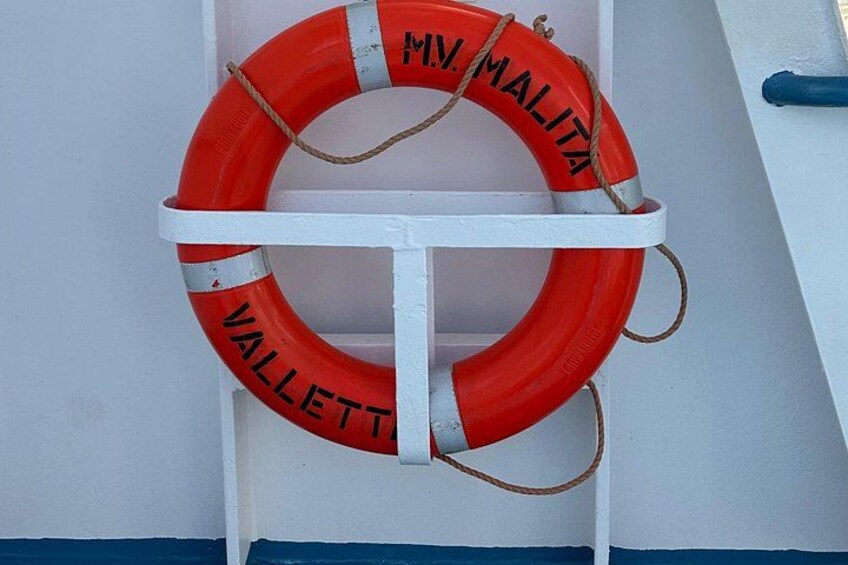 A lifebuoy with 'MV MALITA' and 'VALLETT' text, mounted on a white wall. 5