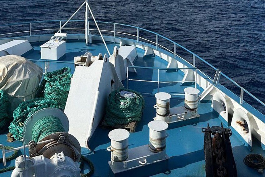 A boat deck with green ropes, white bollards, and a covered area. 2