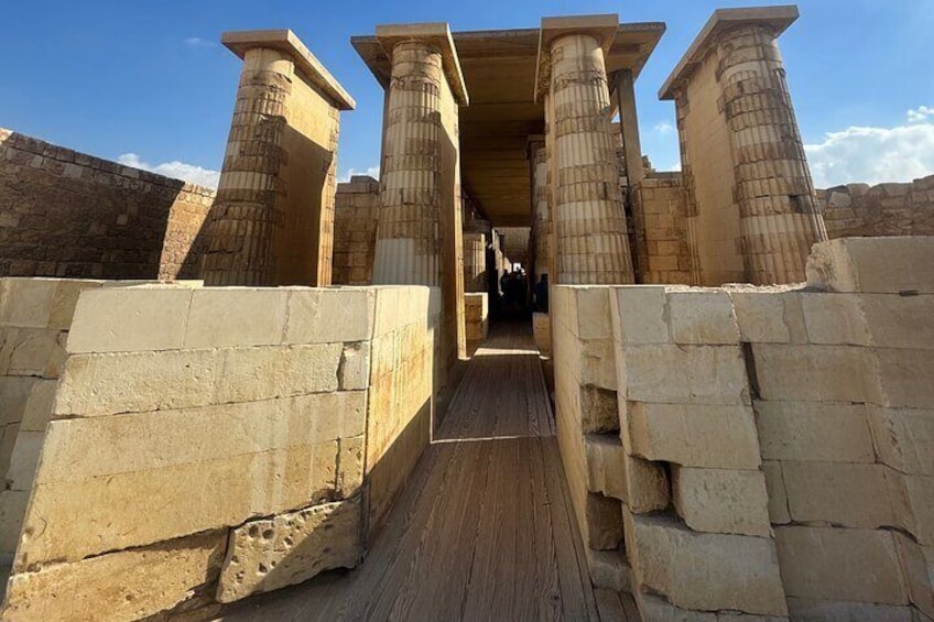 An ancient stone structure with columns and a wooden walkway. 3