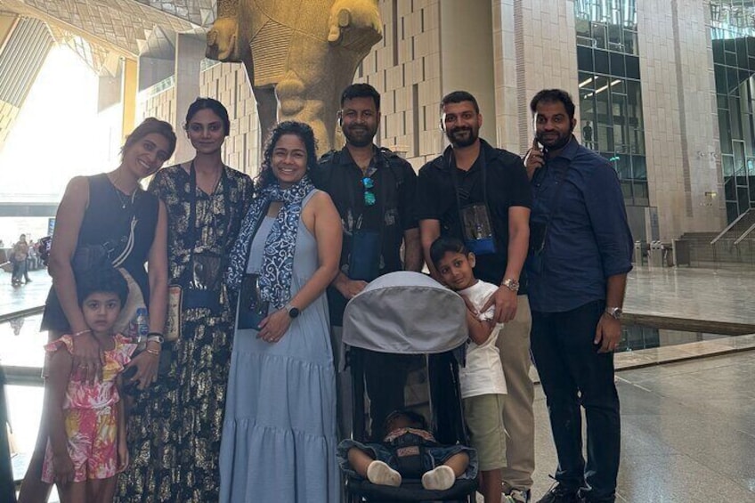 A group of people posing in front of a large sculpture in a modern building. 2