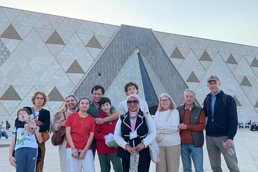 A group of people standing in front of a modern building with a geometric facade. 5