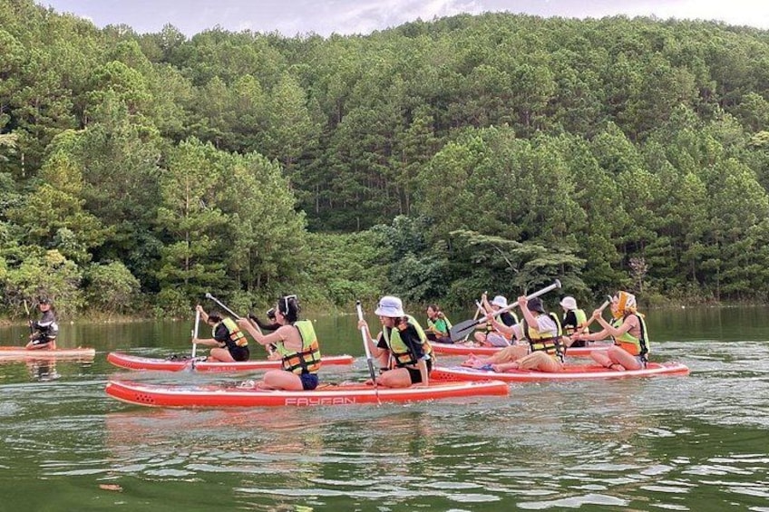 A group of people in red kayaks paddling on a calm river surrounded by dense forest. 4