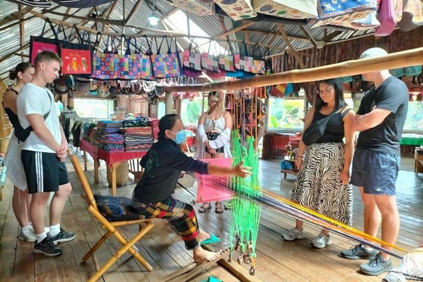 A group of people engaged in weaving at a market stall. 2