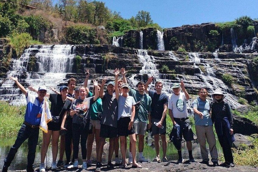 A group of people standing in front of a waterfall. 5