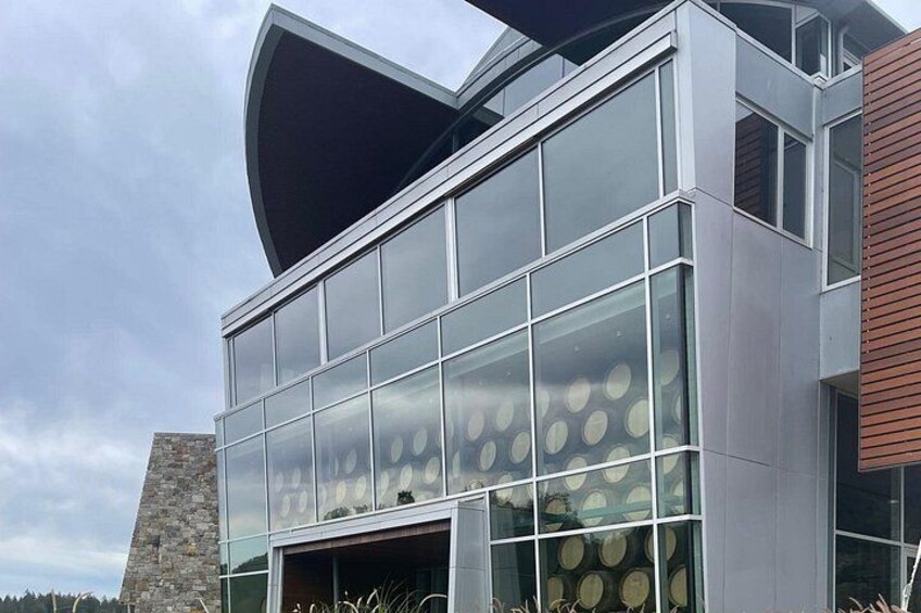 Een modern gebouw met grote glasramen en een opvallende, gebogen dakconstructie. 1