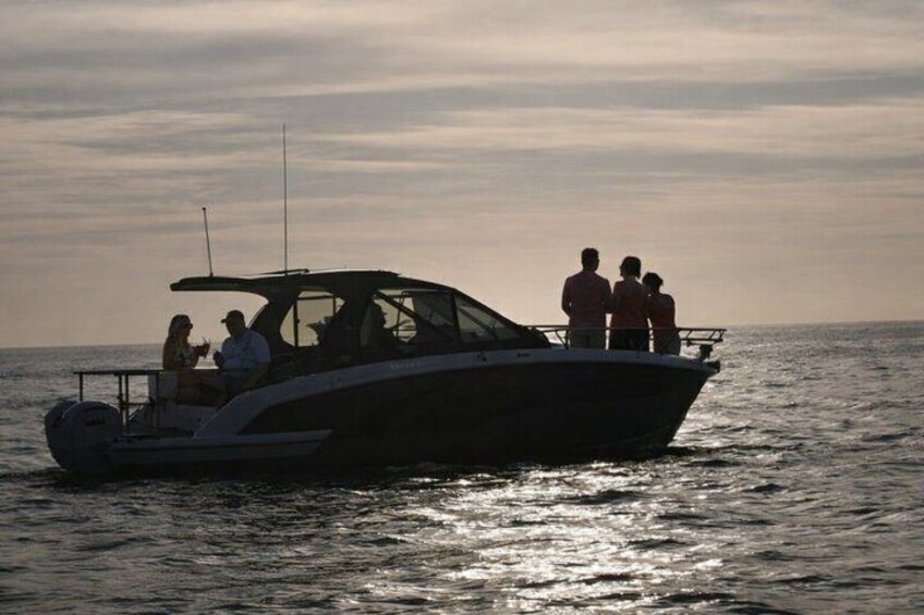 Un barco con pasajeros navegando sobre aguas tranquilas durante el atardecer. 4