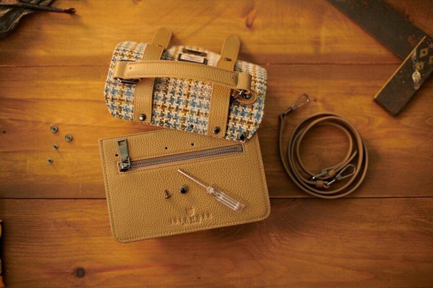 Two handbags on a wooden surface with a belt and a metal tool. 2