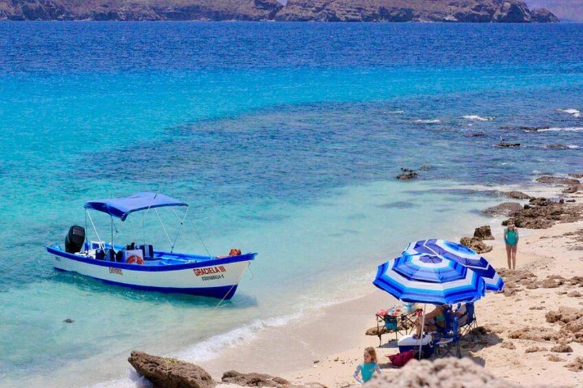 A beach with a boat named 'BRACELIN' and a blue umbrella. 1