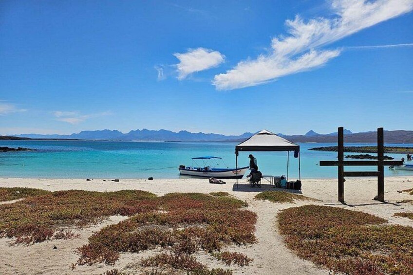 Una playa con una tienda de campaña, un bote y una estructura de madera. 4