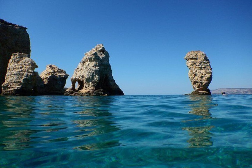 Clear blue waters, rocky formations, and a distant landmass. 2