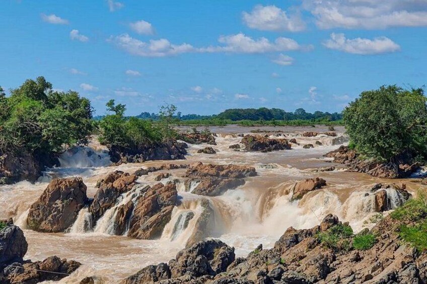 Een waterval met meerdere watertonnen, omgeven door rotsachtig terrein en begroeiing. 5