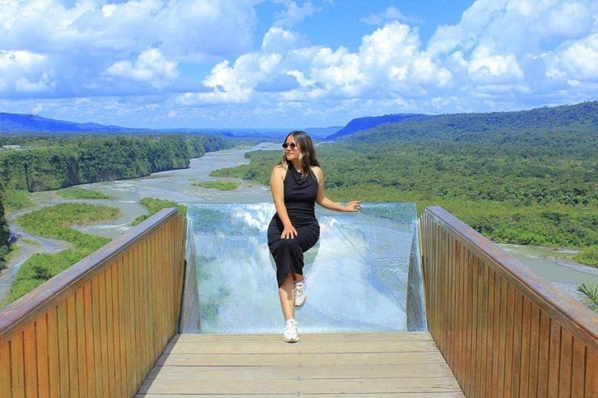 A person on a wooden bridge overlooking a river and green hills. 2