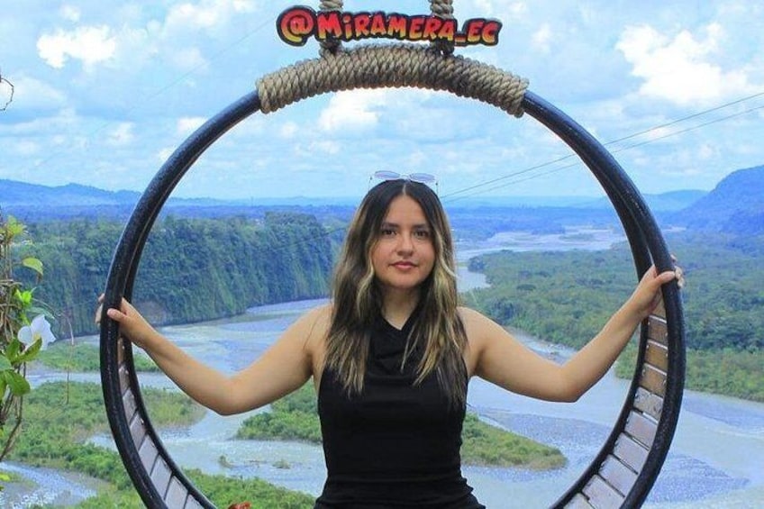 A person holding a circular structure with a river and mountains in the background. 3