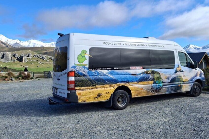 A van with a scenic design, parked on a gravel road with mountains in the background. 3